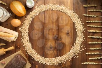 wheat grains and bakery ingredients on wooden background, top view
