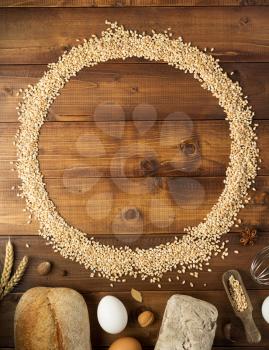 wheat grains and bakery ingredients on wooden background, top view