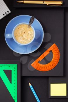 office supplies and cup of coffee at abstract black paper background