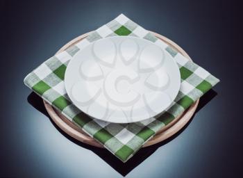 plate, napkin cloth and pizza cutting board at glossy black background