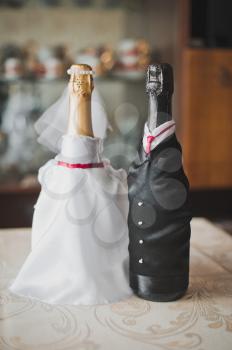 Suits of the groom and the bride on bottles with champagne.