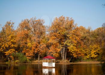 Small house on the lake. An autumn landscape with the lake and a small house with a red roof.
