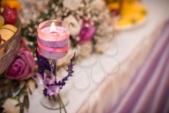 Candle on a table with a bouquet and ornaments.