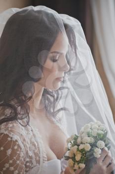 Portrait of the girl in a veil with a bouquet in hands.