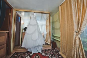 The wedding dress hangs on a case door.