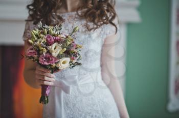 The young bride costs with a bunch of flowers.