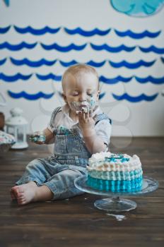Little boy eats with his hands on the cake.