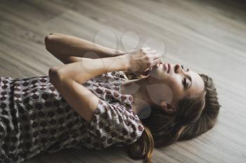 The girl lay on the parquet floor, arms outstretched.