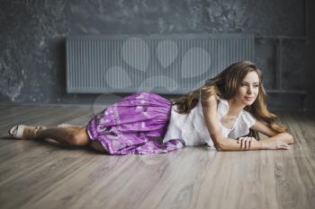 A girl with long brown hair posing on the parquet floor.