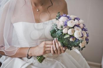 A bouquet of flowers in hands of the bride.