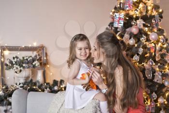 Portrait of the daughter with mother near Christmas tree.