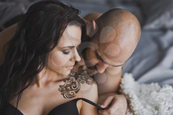 Close-up portrait of a bald brutal man kissing the girl shoulder.