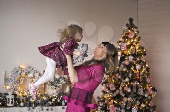 Happy embrace of mother and daughter against the background of the Christmas tree.