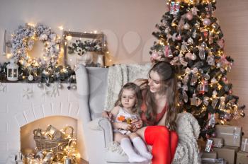 Portrait of a beautiful girl with her daughter on the background of sparkling Christmas garlands.