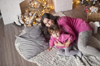 The girl and her mother lying on a blanket near the Christmas tree.
