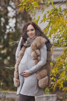 Pregnant girl in among the autumn leaves.
