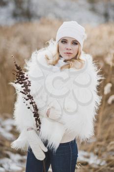 Portrait of a cheerful girl on the winter background of red thickets of reeds.