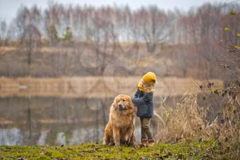 The walk of a child with a big dog on the lake.