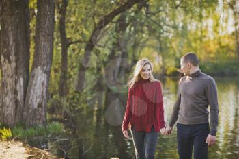 A couple in love walks along the shore of the pond.