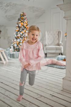 Little girls run around the Christmas decorated house.