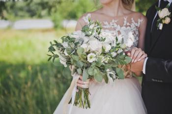 Delicate white-green wedding bouquet in the hands of the bride.