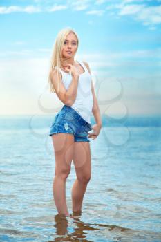 beautiful young blond woman in shorts and t-shirt stands in the warm sea. summer rest