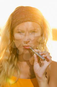 blonde girl with the e-cigarette at sunset.
