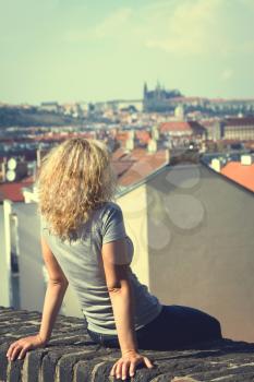 girl sitting on the roof of a house in Prague. top view of the city