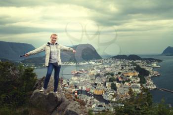 girl standing on a mountain overlooking the city and the ocean. View from Mount Aksla in Alesund, Norway.