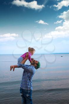 Dad or father and his baby daughter hugging on a boat or ferry in the sea on a cool summer day