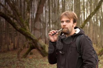 man with the electronic cigarette in the park autumn