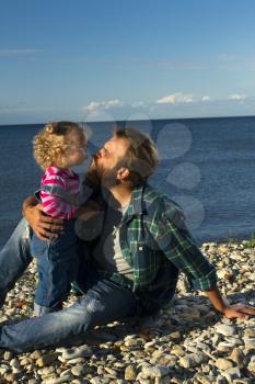 Daughter kissing daddy on the beach. family holiday