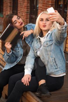 two friends reading a book on the street. do selfie