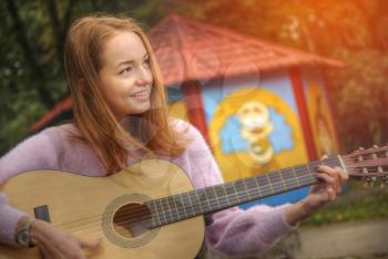 girl with a guitar playing in the park