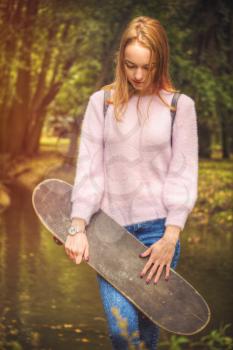 girl is holding a skate in the park