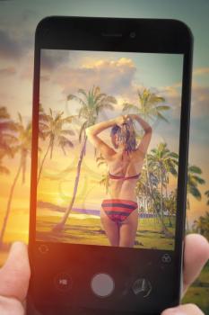 Photographing a blogger on a mobile phone. girl in a swimsuit standing on the beach