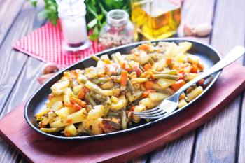fried vegetables with meat on plate and on a table