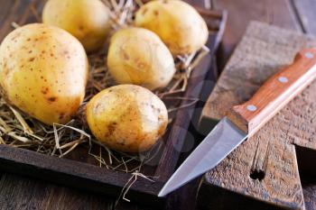 raw potato in wooden box and on a table