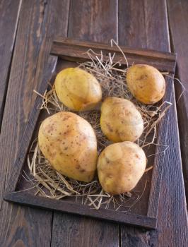 raw potato in wooden box and on a table