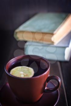 tea with lemon in cup and old books