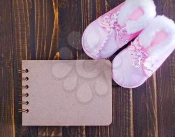 baby shoes and notepad for note on a table