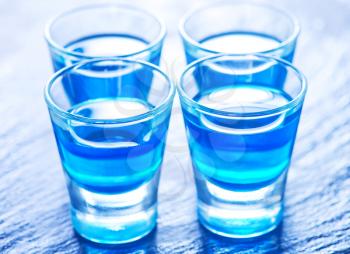 blue alcoholic drink into small glasses on a table
