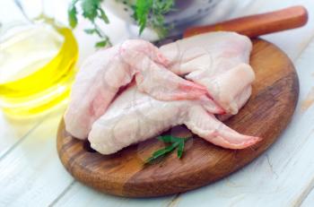 Raw chicken and knife on the wooden board