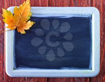 autumn background, black board and autumn leaves on a table