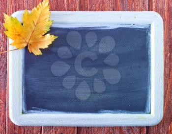 autumn background, color leaves and black board on a table