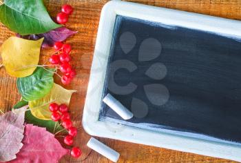 autumn background, color leaves and black board on a table