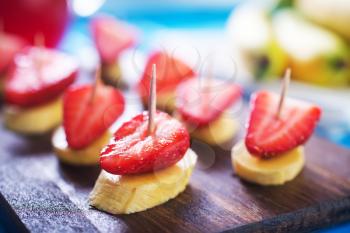 canape with strawberry and banana on wooden board