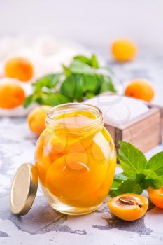 apricots with sirup in glass bank and on a table