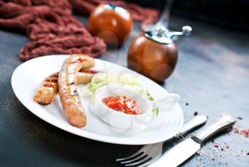 grilled sausages with sauce on white plate