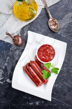smoked sausages with tomato sauce, sausages with sauce on plate